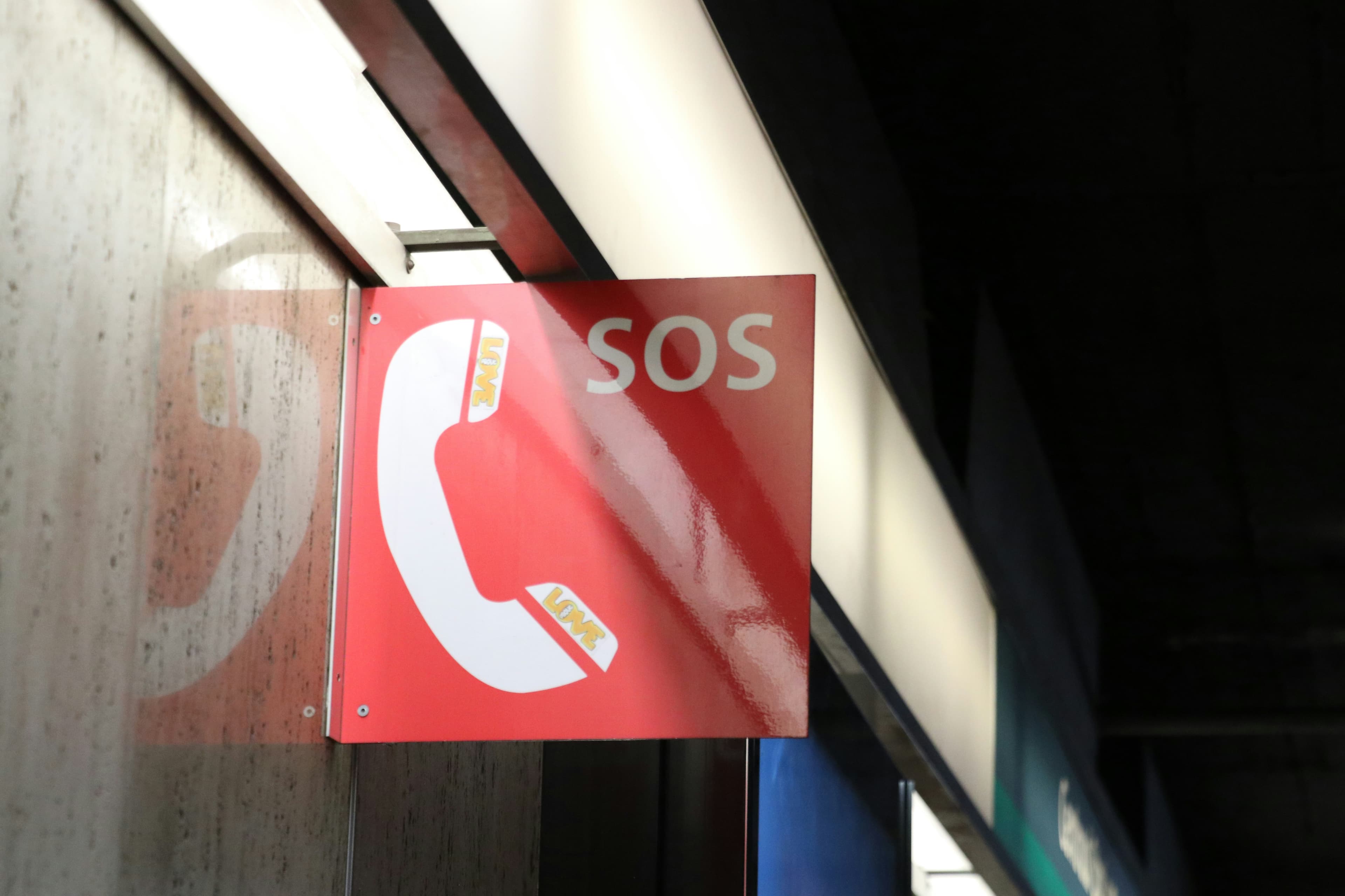 Rotes SOS-Notrufschild mit weißem Telefonhörer-Symbol an einer Wand.